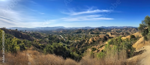 Scenic panoramic view of rolling hills and valleys under a clear blue sky with lush greenery in a serene landscape setting