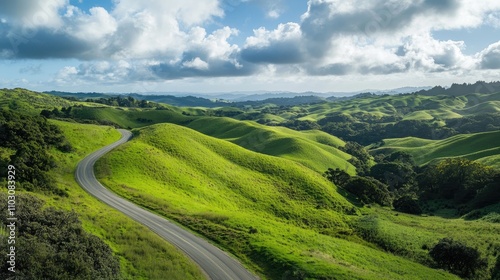 Lush green hills undulate beneath a partly cloudy sky, with a winding road inviting exploration and adventure through the serene landscape.