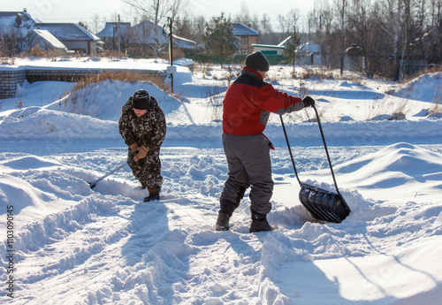 Photography Two men are shoveling snow with a large black plastic bag