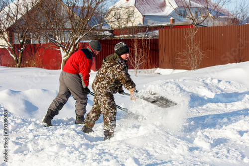 Картината върху платно Two men are shoveling snow in front of a house