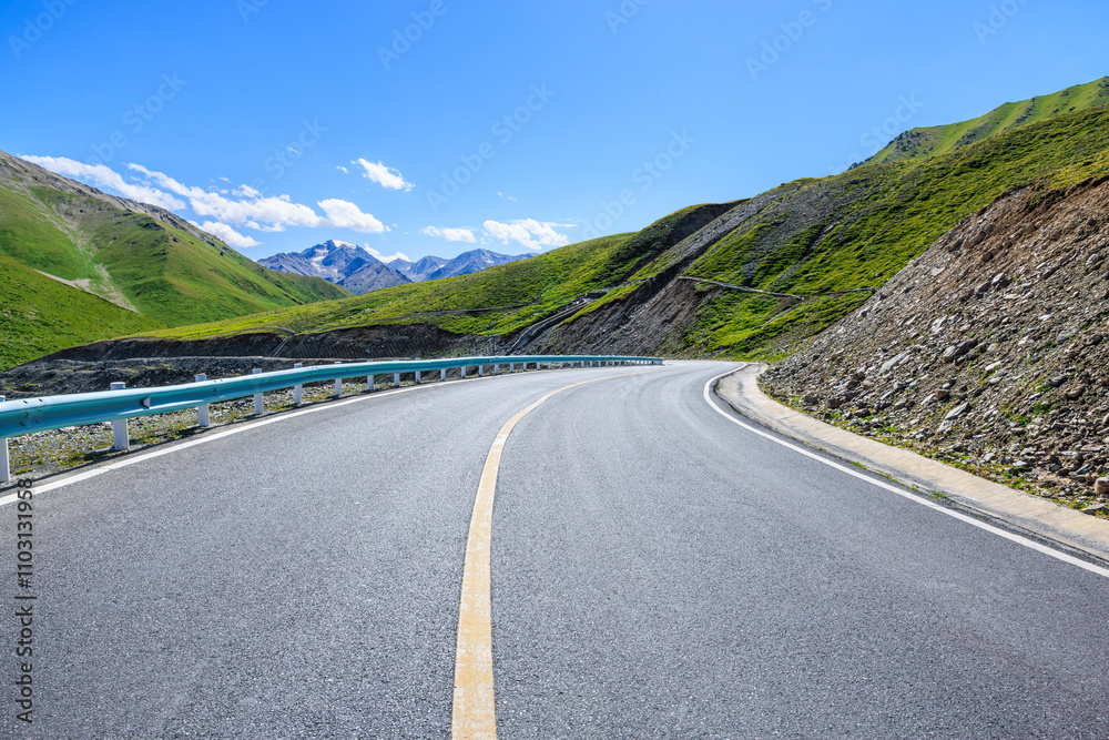 Naklejka premium Countryside asphalt road and green meadow with mountain nature landscape on a sunny day. Road trip.