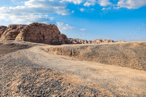 Desert gravel road and Yardang landform mountain natural landscape in Xinjiang, China. Outdoor natural background.