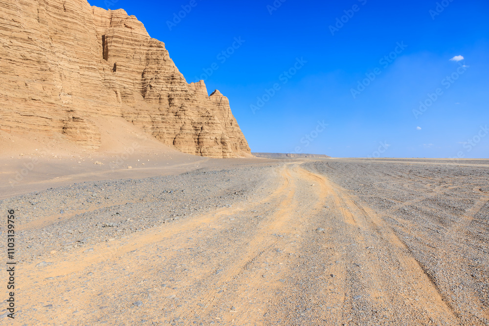 Desert sand road and Yardang landform mountain natural landscape in Xinjiang, China. Road trip in no man's land. Outdoor natural background. Desert sand road and Yardang landform mountain natural landscape in Xinjiang, China. Road trip in no man's land. Outdoor natural background.