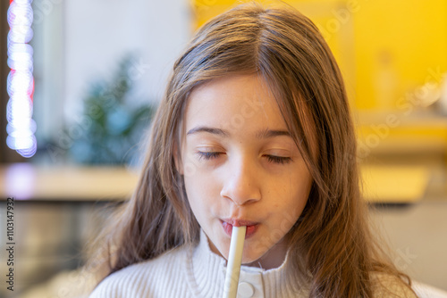A happy girl drinks a prepared drink in a cafe. A girl with a drink.