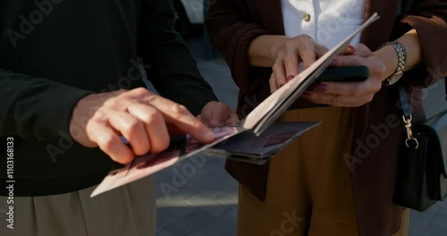 The realtor and the buyers are considering a booklet with a house design project. Close-up of their hands, unrecognizable persons