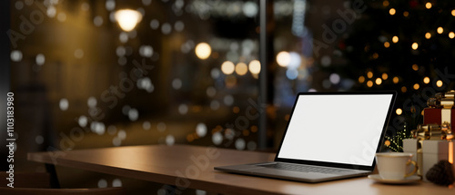 A laptop on a table in a room at night with a Christmas tree and street lights in the background.