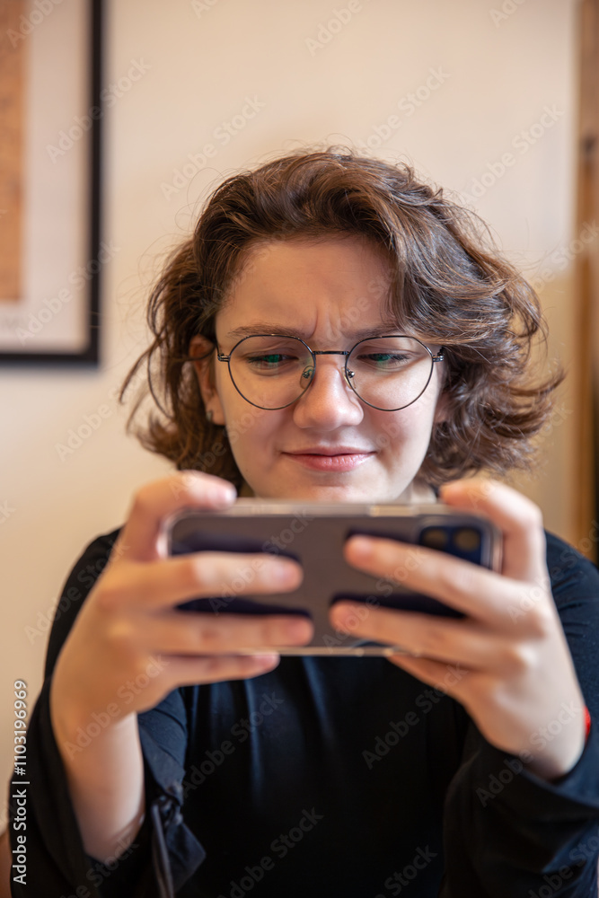 Young female gamer playing games on the phone in a cafe. Emotions concept. Young female gamer playing games on the phone in a cafe. Emotions concept.