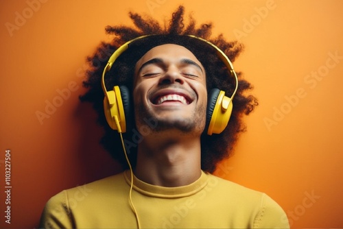 Obraz na płótnie Joyful person wearing bright yellow headphones, smiling and enjoying music. Vibrant orange background emphasizes happiness, relaxation, and the fun of listening to favorite tunes w salonie