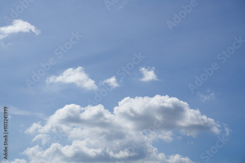 Bright blue sky with fluffy white clouds, perfect for backgrounds or nature themes. Clear and serene atmosphere, ideal for creative projects or designs.