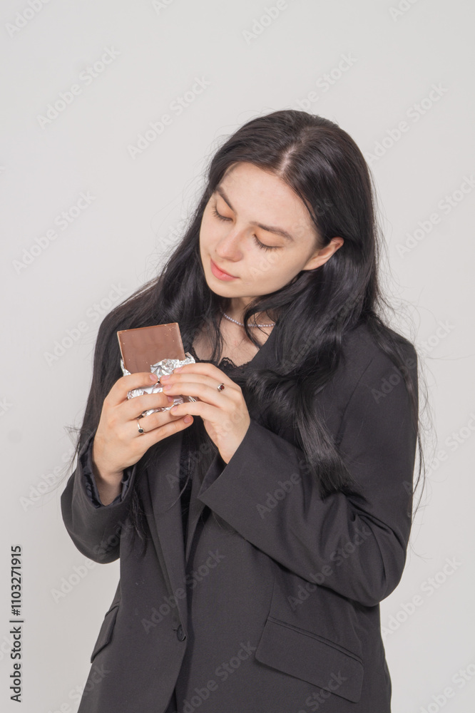 Cute young brunette with a chocolate bar on a white background. Copy space Cute young brunette with a chocolate bar on a white background. Copy space