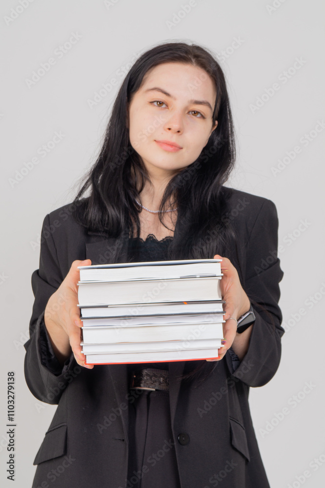 Young cute brunette girl with a stack of books on a white background. Copy space Young cute brunette girl with a stack of books on a white background. Copy space
