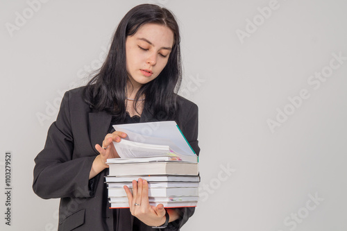 Young cute brunette girl with a stack of books on a white background. Copy space