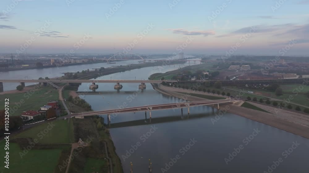 Aerial view of Nijmegen cityscape featuring the Waalbrug bridge, Stevenskerk church, and the Waal river at sunrise, Gelderland, The Netherlands. Aerial view of Nijmegen cityscape featuring the Waalbrug bridge, Stevenskerk church, and the Waal river at sunrise, Gelderland, The Netherlands.