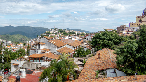 Beautiful view of Taxco with traditional architecture and lush mountains under a blue sky