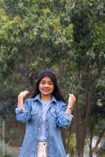 Portrait of serious beautiful female, looks smiling at camera, stands against natural background stock photo