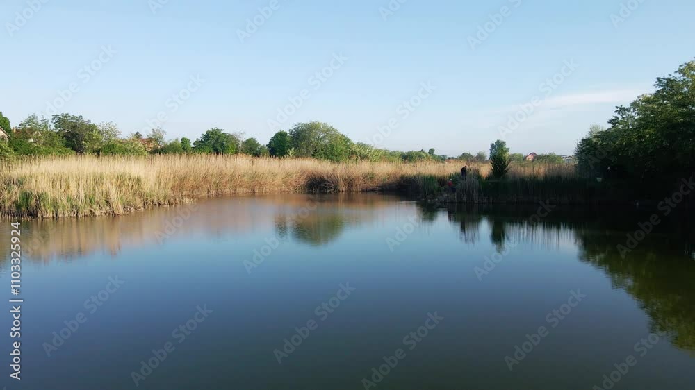 Calm waters reflect the landscape in a serene natural setting under clear blue skies Calm waters reflect the landscape in a serene natural setting under clear blue skies