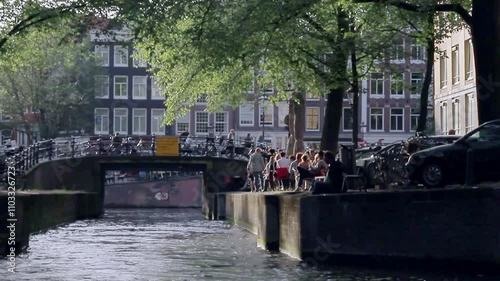 Travelling along a narrow Amsterdam canal on a summer evening. Amsterdam, Holland.
