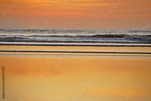 
Beautiful golden seascape with reflections of golden sunlight, ocean waves, sunrise on the coast near the beach in summer day.