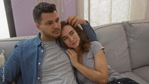 Man and woman relaxing together on a sofa in a cozy living room, displaying love and companionship in an indoor home setting