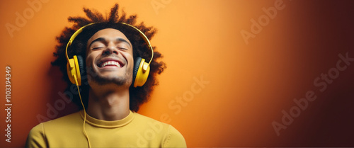 Obraz na płótnie Banner of poyful young man wearing bright yellow headphones, smiling and enjoying music. Vibrant orange background emphasizes happiness, relaxation, and the fun of listening to favorite tunes w salonie
