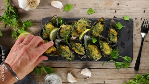 woman's hand is taking a mussel with butter and parsley. Festive French food