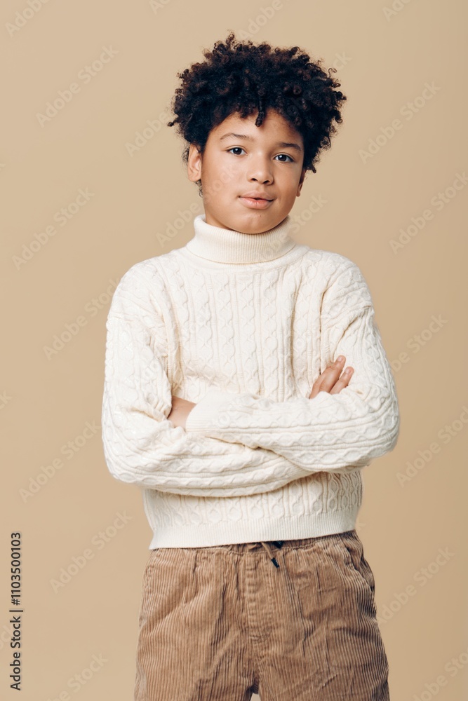Young african american boy wearing white sweater and brown pants standing confidently against a simple beige background Young african american boy wearing white sweater and brown pants standing confidently against a simple beige background