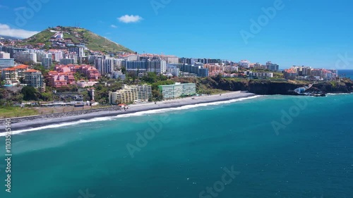 Aerial view of turquoise waters of Praia Formosa beach and colorful houses and hotels on hills in Funchal Madeira island Portugal
