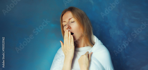 Sleepy lazy young woman yawns wakes up after sleep in blanket in morning at home