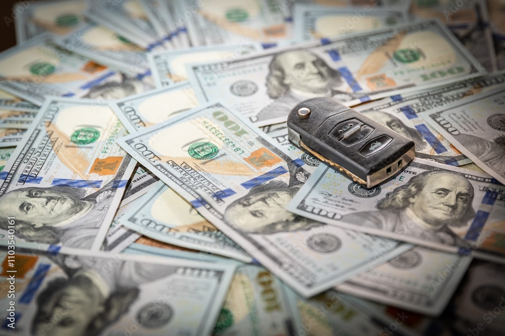 Car Key on US 100 Dollar Bills Background, Concept of Wealth and Vehicle Ownership Car Key on US 100 Dollar Bills Background, Concept of Wealth and Vehicle Ownership