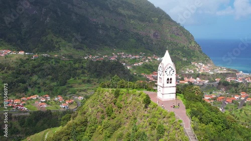 Historic clock tower Capelinha de Nossa Senhora de Fatima surrounded by lush green terraced landscape and blue ocean Madeira island Portugal photo