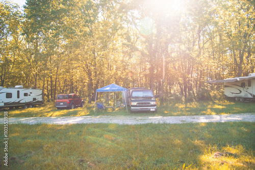 Outdoor pop-up canopy camping chair setup at country park in Mansfield, Missouri, lush green trees and gravel road, grassy field, RV trailer campsite campground, nature outdoor living background photo