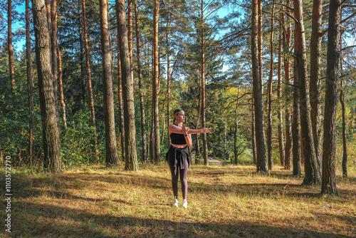 young woman is exercising in the forest, embodying a healthy, active lifestyle. This outdoor workout highlights fitness, nature, and youth-focused wellness, promoting strength, endurance, and physical