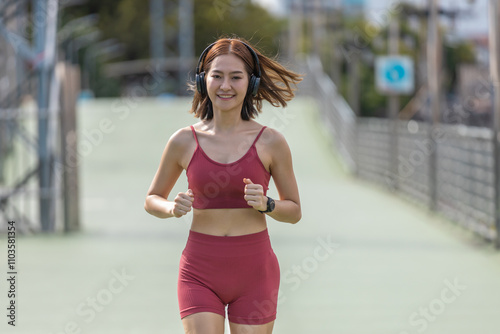 Young beautiful woman sportswear workout clothes wear headphone exercise running in street city before morning run. Asian strong female sporty sportswear jogging outdoors. fitness healthy concept.