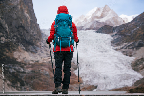 Backpacking woman watching the large hanging glacier on high altitude mountain top photo