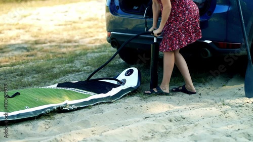 Wallpaper Mural Woman pumps up paddleboard next to car for an outdoor trip Torontodigital.ca