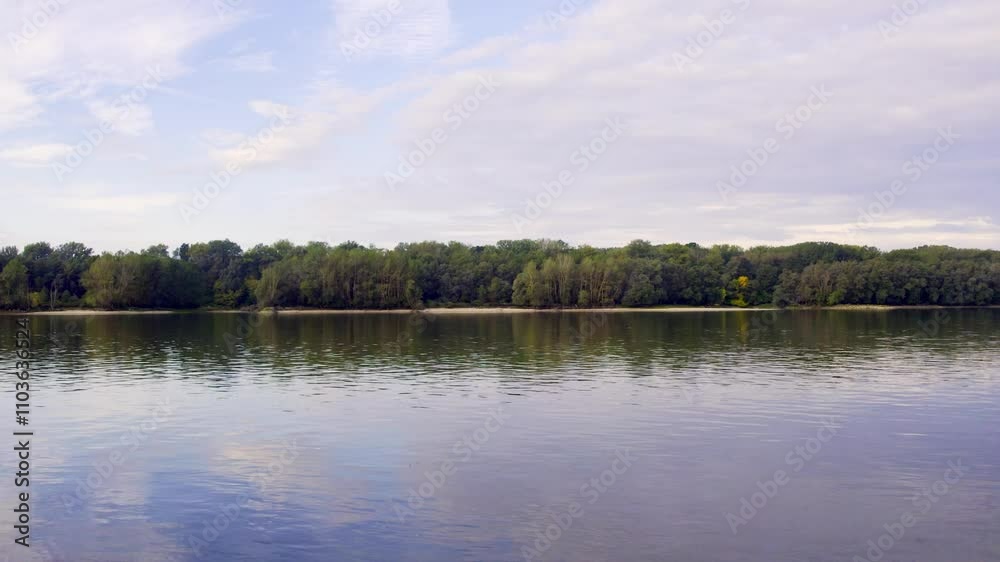 Calm waters reflect the lush greenery along the serene riverbank during a tranquil afternoon Calm waters reflect the lush greenery along the serene riverbank during a tranquil afternoon