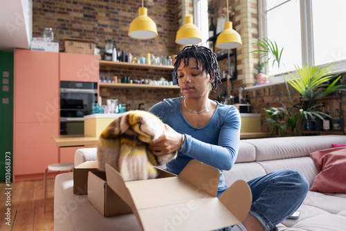 Young African American woman packing clothing into a box to ship