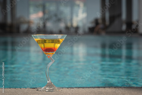 Aperol Spritz Cocktail Glass by a swimming pool
 photo