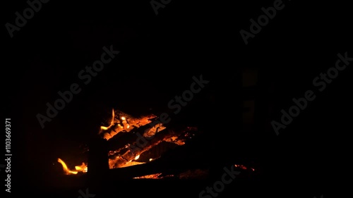 The fireplace in the house burns like a bonfire on natural wood and branches from the forest. The fire is actively burning, a tree falls and flares up