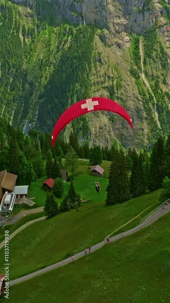 Aerial view beautiful of Paraglider flying with a picture of the Swiss flag on it in the alpine mountains in Switzerland