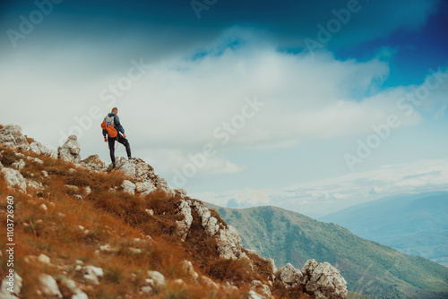 A male climber standing on the top of rocky mountain peak cliff, adventure travel, extreme sport outdoor.
