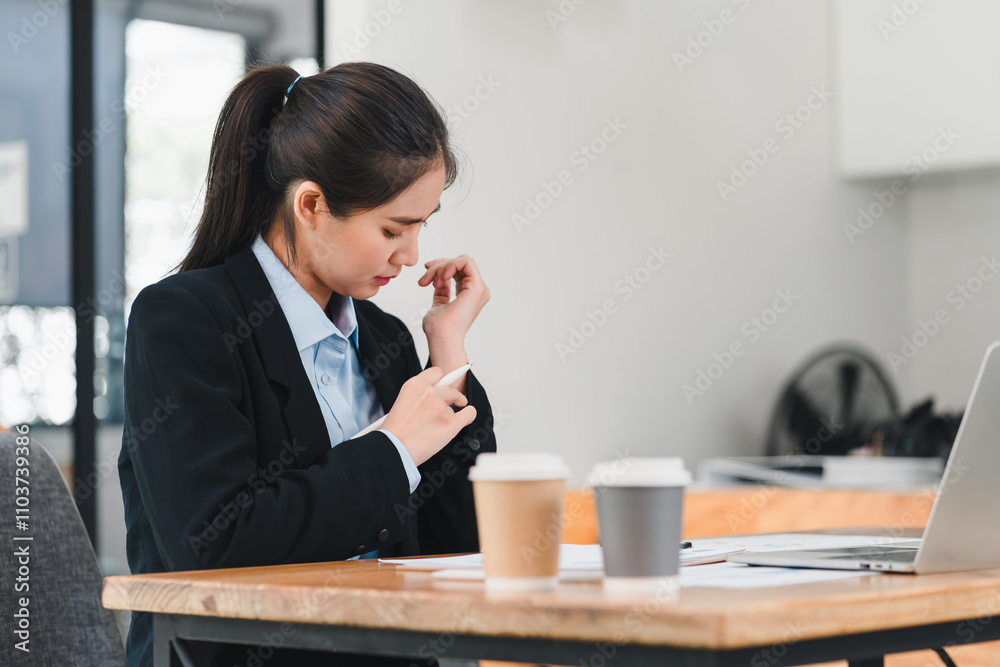 focused woman in business suit sits at table, reviewing documents with coffee cups nearby. She appears engaged and thoughtful in modern office setting focused woman in business suit sits at table, reviewing documents with coffee cups nearby. She appears engaged and thoughtful in modern office setting