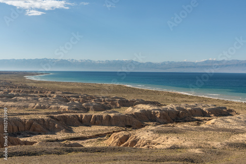Fototapeta Naklejka Na Ścianę i Meble -  Vast expanse of arid dry landscape and blue water at the shore of Issyk-Kul lake