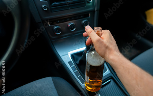 Man with a bottle of beer in the car. Drunk driving concept. photo