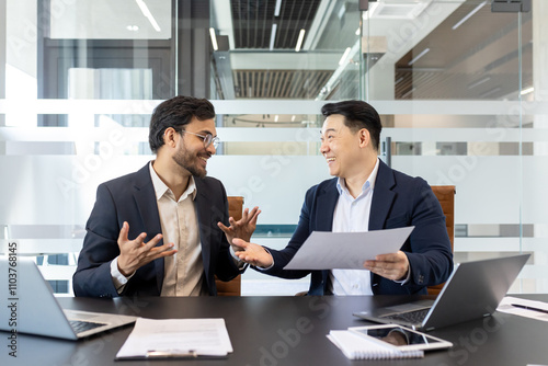 Fényképezés Businessmen conversing in office while reviewing documents, showcasing teamwork and collaboration