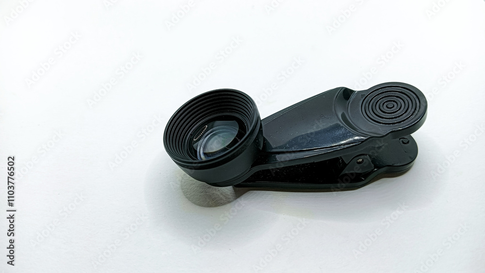 A black clip-on camera lens accessory with a reflective glass surface placed on a plain white background A black clip-on camera lens accessory with a reflective glass surface placed on a plain white background