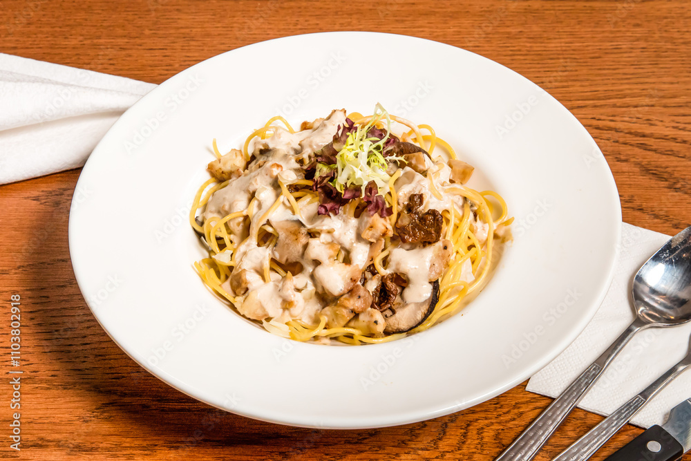 Chicken Spaghetti with Porcini Cream Sauce served in plate isolated on wooden table side view of italian cousin Chicken Spaghetti with Porcini Cream Sauce served in plate isolated on wooden table side view of italian cousin