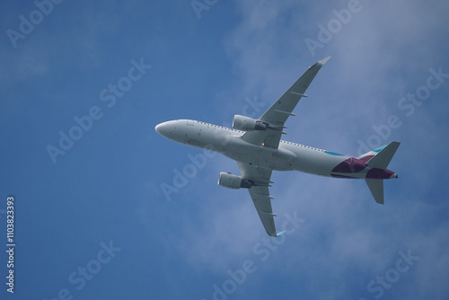 White passenger aircraft, airplane flying in blue sky, from the bottom