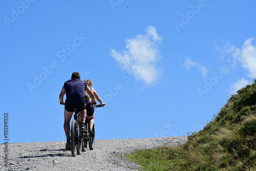 Zwei Mountainbiker auf Schotterweg vor blauem Himmel photo