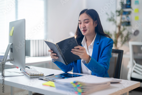 A woman is sitting at a desk reading a book